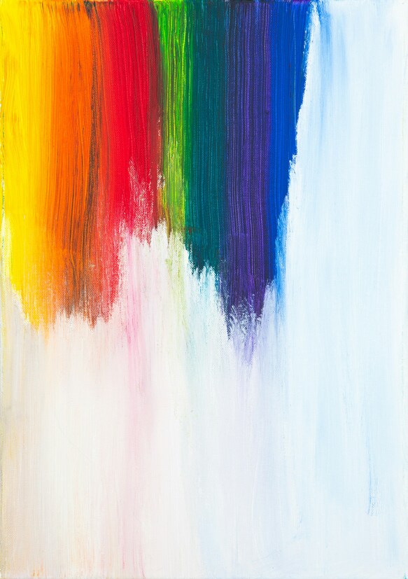 A swipe of rainbow paints on a light colored canvas.